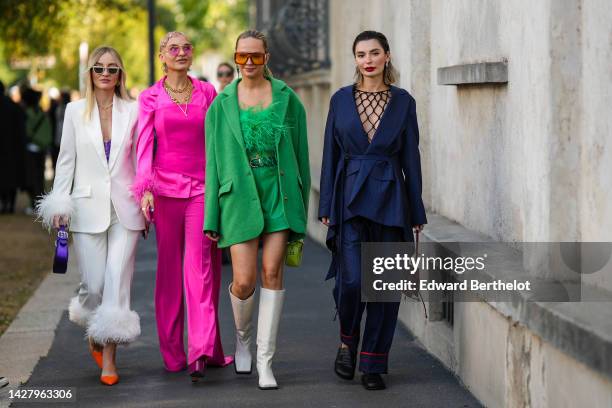 Guest wears white sunglasses, gold earrings, gold necklaces from Chanel, a white blazer jacket with embroidered feathers wrists, matching white suit...