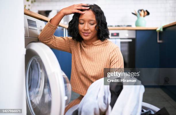 laundry, house work and a stress woman in kitchen taking clothes out of washing machine. tired, cleaning and a frustrated lady on the floor. overworked, lonely and a depressed housewife busy at home - droger stockfoto's en -beelden