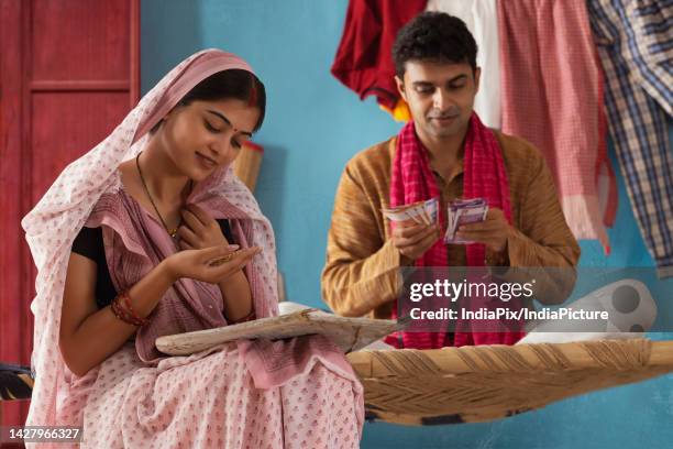 woman cleaning paddy seeds at home while her husband counting bank notes - bihar stock pictures, royalty-free photos & images