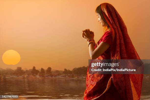 woman from bihar offers prayers to the sun in the early morning hours during chhath puja festival - hinduism stock pictures, royalty-free photos & images