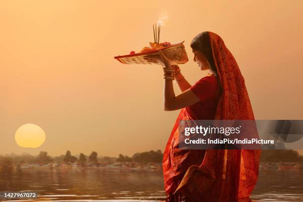 woman from bihar offers prayers to the sun in the early morning hours during chhath puja festival - chhath festival - fotografias e filmes do acervo