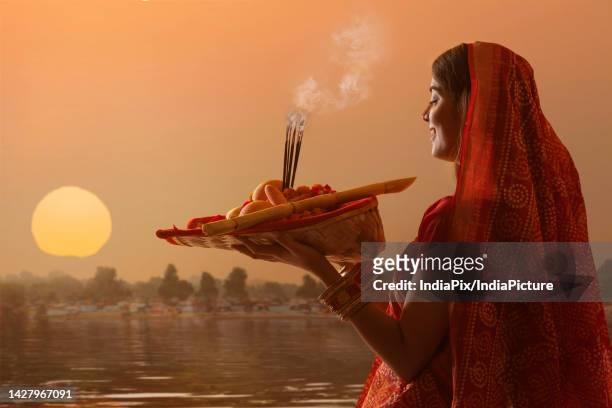 woman from bihar offers prayers to the sun in the early morning hours during chhath puja festival - chhath festival stock-fotos und bilder