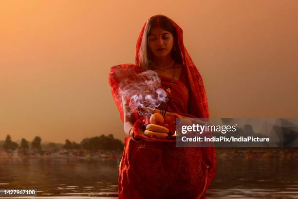 woman from bihar offers prayers to the sun in the early morning hours during chhath puja festival - chhath festival - fotografias e filmes do acervo
