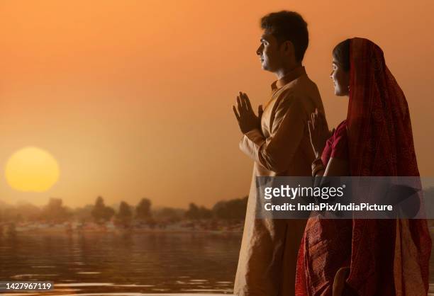 couple from bihar offers prayers to the sun in the early morning hours during chhath puja festival - chhath festival stock-fotos und bilder