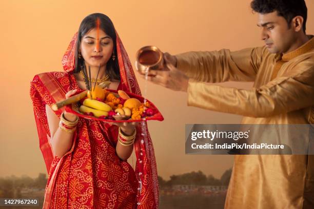 couple from bihar offers prayers to the sun in the early morning hours during chhath puja festival - chhath festival - fotografias e filmes do acervo
