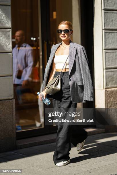 Guest wears black sunglasses a white latte square-neck / cropped tp, a gold shiny leather large 2.55 crossbody bag from Chanel, black large wide legs...