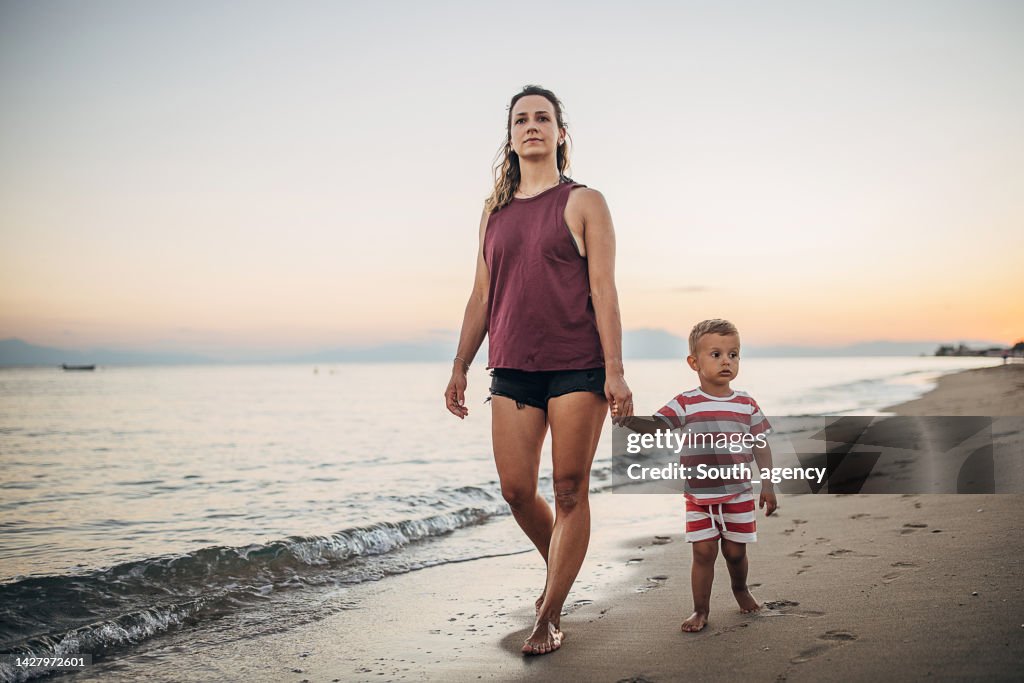 Una madre y su hijo caminando por la playa