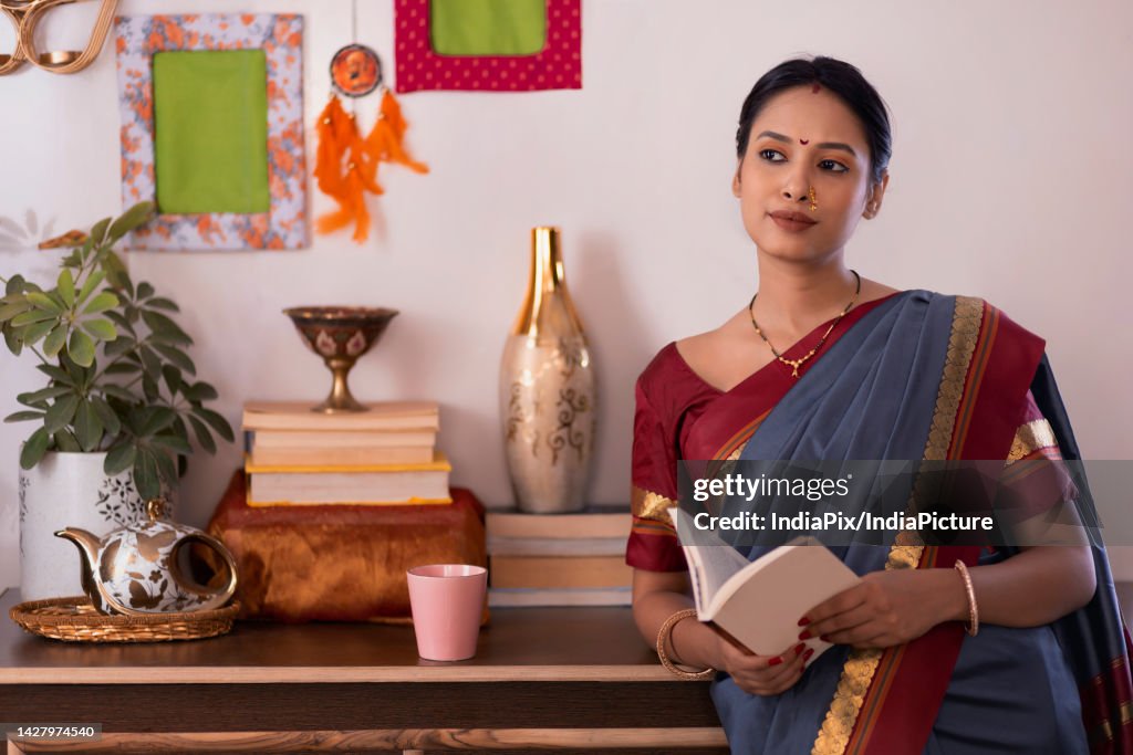 Portrait of a young woman reading books in living room