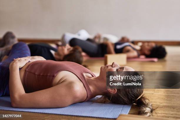 meditação, yoga e pessoas em um estúdio de bem-estar ou clube de fitness para cuidados mente, corpo e espiritual. relaxe, calma e descansando mulher no chão com grupo para exercício de respiração, zen e na aula de ginástica - yoga studio - fotografias e filmes do acervo