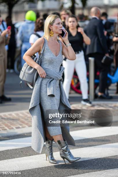 Guest wears a gold long pendant earrings, a pale grau ribbed wool V-neck / tank-top / long midi dress, a pale gray jacket, a pale gray leather...