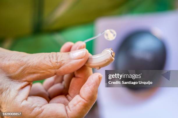 close-up of senior woman holding a modern hearing aid - hearing aid - fotografias e filmes do acervo