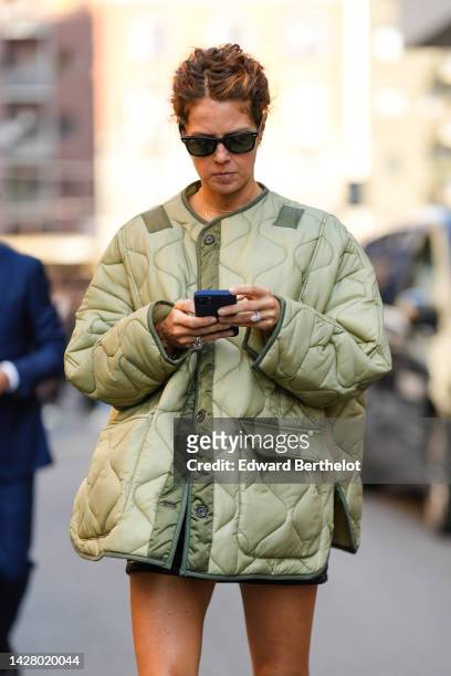 Guest wears black sunglasses, a khaki quilted oversized jacket, black shorts, silver and diamonds rings , outside Missoni, during the Milan Fashion...