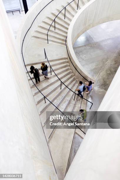 looking down view onto curved staircase with blurred motion of people. - spiral staircase stock pictures, royalty-free photos & images