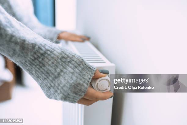 economic crisis and despair in cold houses. control thermostat temperature on radiator - feber bildbanksfoton och bilder
