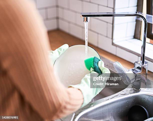 kitchen, clean and hygiene by woman washing dishes at kitchen sink, cleaning a dirty plate with fresh water. housework, task and domestic care with female hand dishwashing, closeup declutter activity - wash the dishes stockfoto's en -beelden