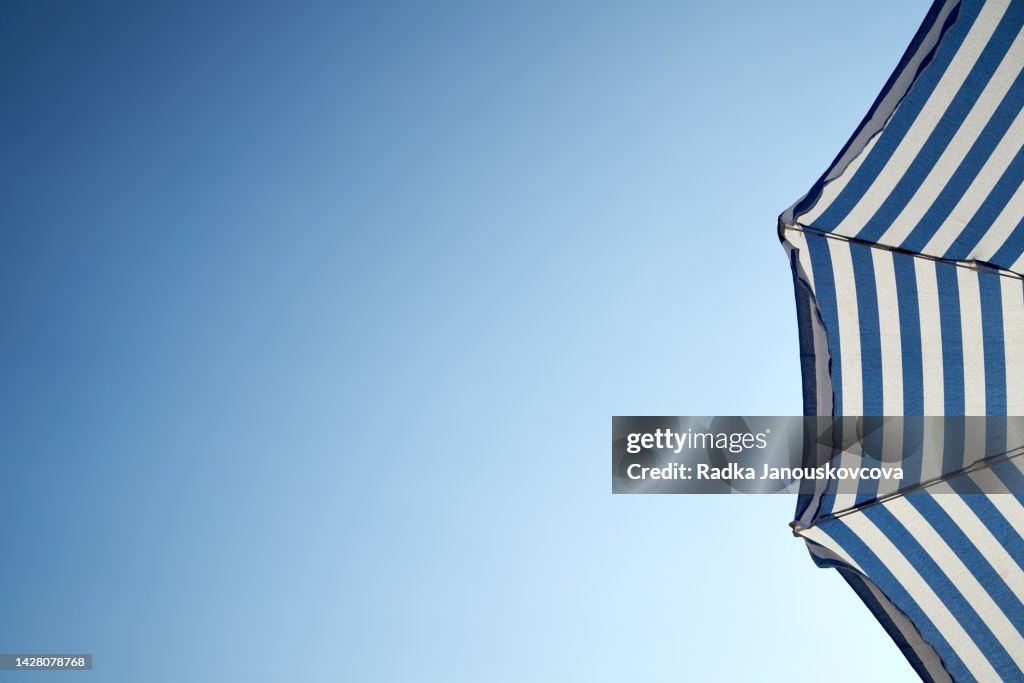 White and blue umbrella against blue sky with copy space