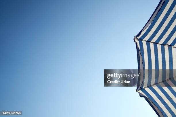 white and blue umbrella against blue sky with copy space - parasol photos et images de collection