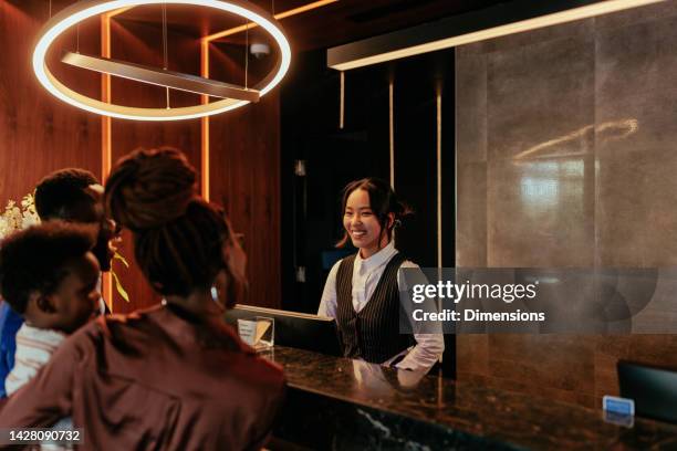 happy receptionist talking to hotel guests. - lodge stock pictures, royalty-free photos & images