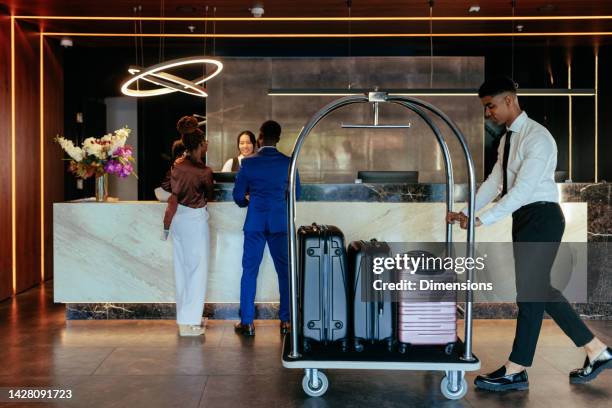 hotel attendant with luggage in lobby. - lodge stock pictures, royalty-free photos & images