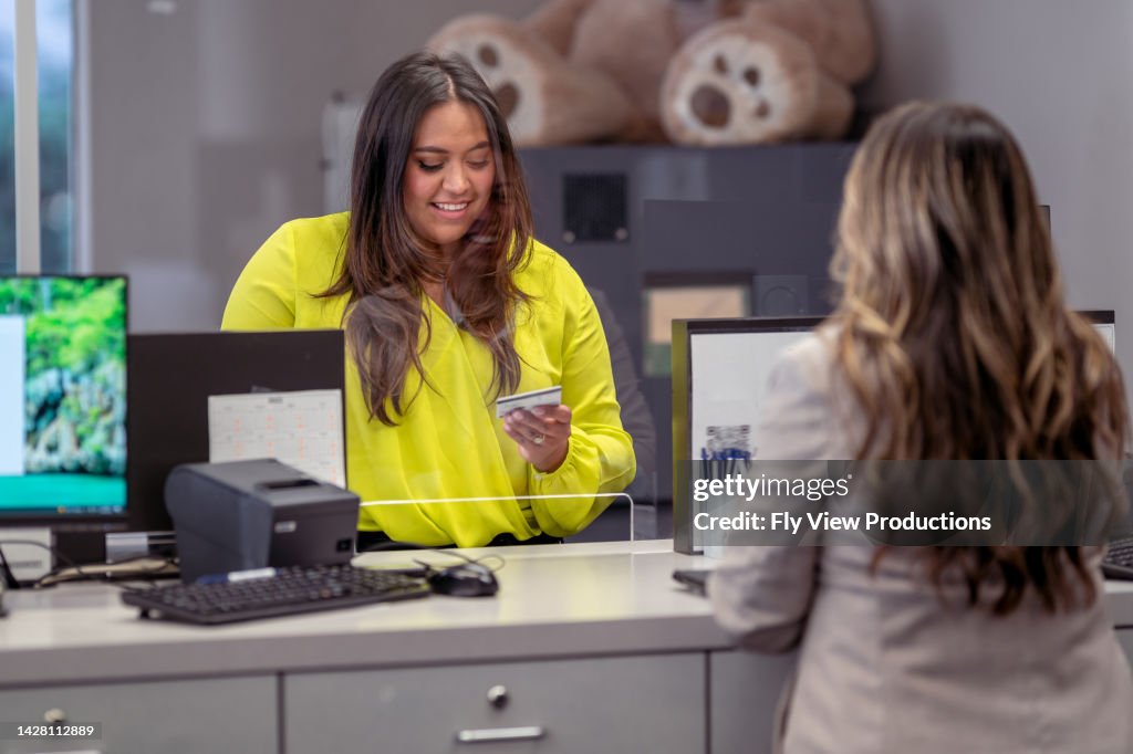 Woman handing bank teller her credit card