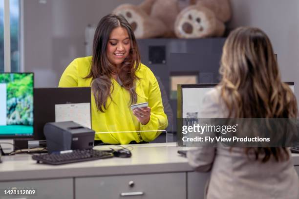 woman handing bank teller her credit card - bank office clerks stock pictures, royalty-free photos & images