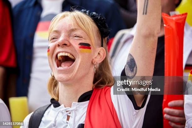 glücklicher deutscher fußballfan, der beim spiel der deutschen nationalmannschaft mit einem arm in der luft singt und jubelt - afl woman stock-fotos und bilder