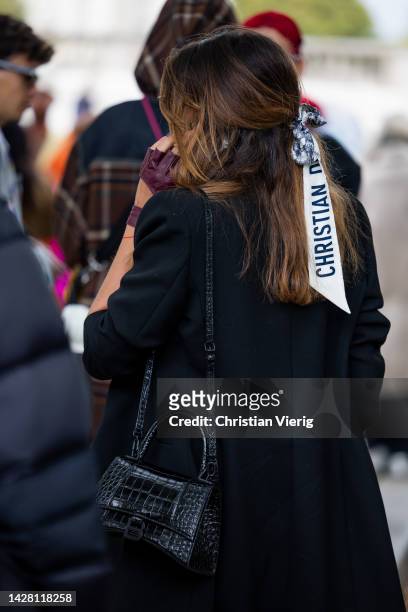 Guest wears black Balenciaga bag, burgundy cut out gloves, hair band Dior, black blazer, pants outside Victoria/Tomas during Paris Fashion Week -...