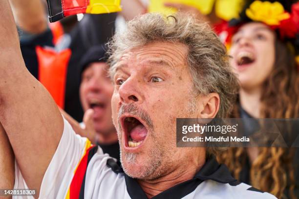 un fan de football allemand mature excité célébrant après que l’équipe ait marqué un but dans un stade bondé - south american u 20 soccer women photos et images de collection