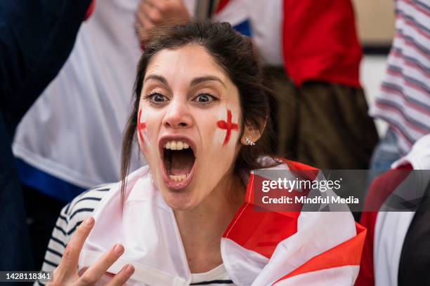 young english woman cheering for england's national team in crowded stadium - geschminkt gezicht stockfoto's en -beelden