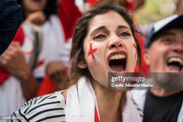 fan de football anglais avec un drapeau anglais enroulé autour du cou pour encourager l’équipe nationale de football - south american u 20 soccer women photos et images de collection