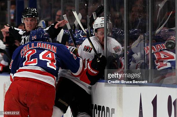 Daniel Alfredsson of the Ottawa Senators is checked into the boards along the bench in the first period by Ryan Callahan of the New York Rangers in...