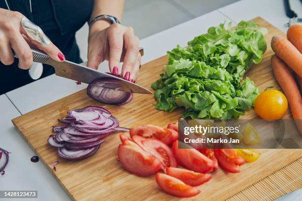 a woman in the kitchen, slicing a spanish red onion, preparing vegan food - cutting red onion stock pictures, royalty-free photos & images