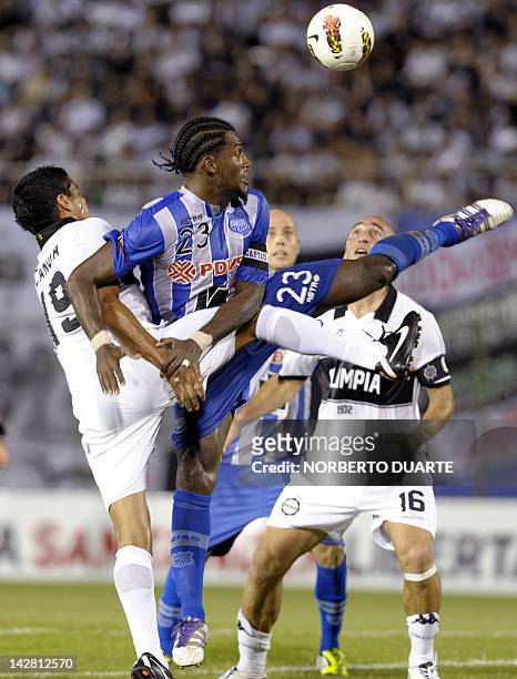 Footballer Gabriel Achilier , of Ecuador’s Emelec, and Salustiano Candia of Paraguay's Olimpia, jump for the ball during a Libertadores Cup match...