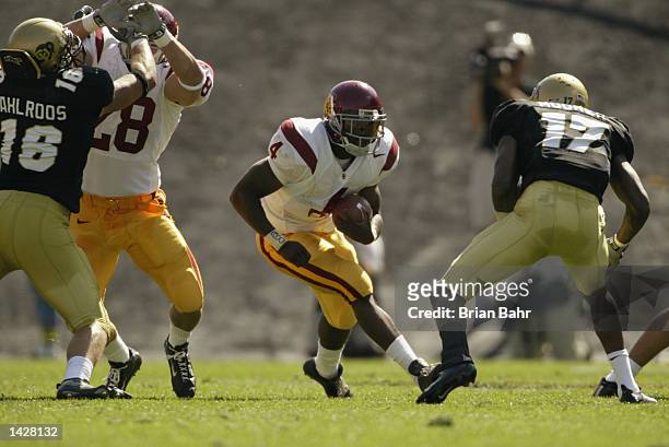 Sultan McCullough of the USC Trojans runs with the ball evading the defensive pressure by Medford Moorer of the Colorado Buffaloes for a touchdown in...
