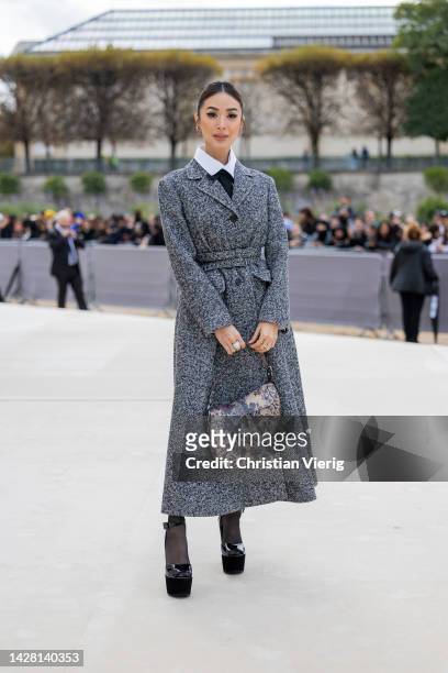 Heart Evangelista wears grey belted coat, bag with graphic print, white button shirt, platform shoes outside Dior during Paris Fashion Week -...