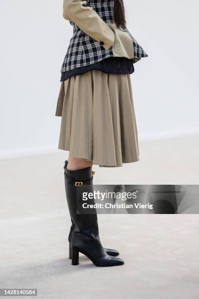 Lucie Zhang wears brown beige pleated asymmetric skirt, tailored checkered black white jacket, knee high boots outside Dior during Paris Fashion Week...