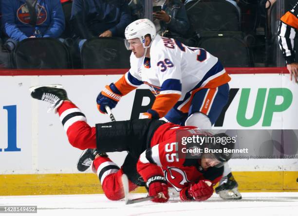 Dennis Cholowski of the New York Islanders trips up Mason Geertsen of the New Jersey Devils during the first period at the Prudential Center on...