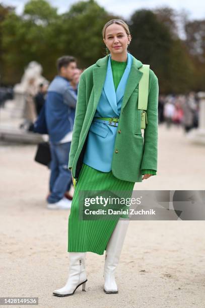 Guest is seen wearing a green jacket, light blue blazer, green dress and white boots with alligator earring outside the Dior show during Paris...