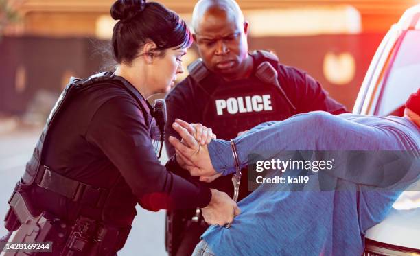 policewoman and partner, handcuffing man - arrest stock pictures, royalty-free photos & images