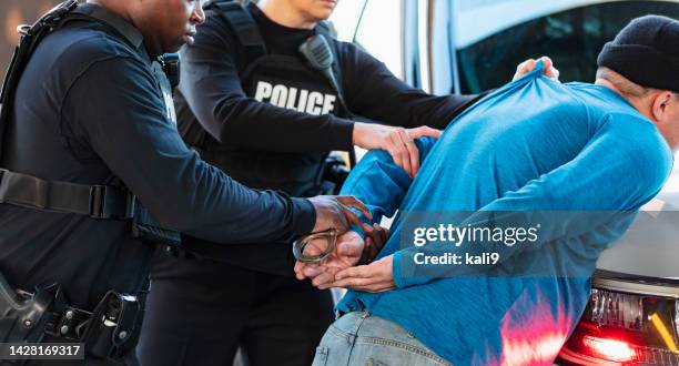 two police officers arresting a suspect, handcuffing - bonnet hat stock pictures, royalty-free photos & images