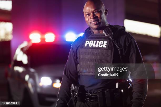 african-american policeman at night with patrol cars - police officer smiling stock pictures, royalty-free photos & images