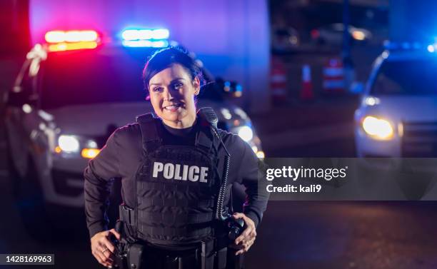 policewoman at night by police car, lights flashing - mulher polícia imagens e fotografias de stock