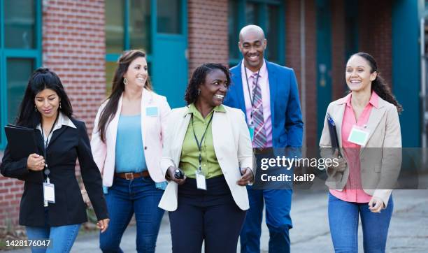 group of teachers walking together outside school - ids center stock pictures, royalty-free photos & images