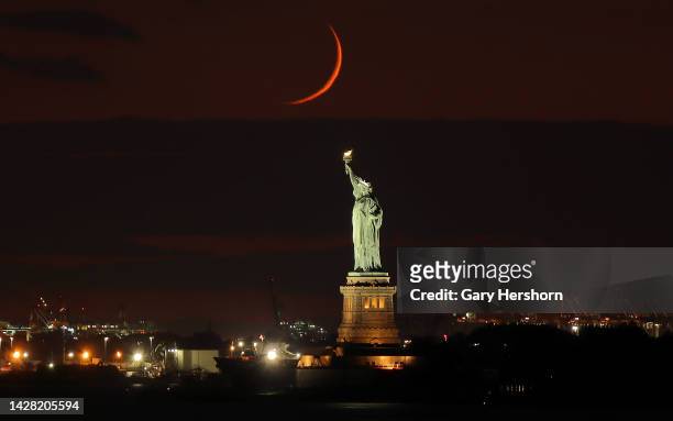Percent crescent moon sets behind the Statue of Liberty as the sun sets on September 27 in New York City.