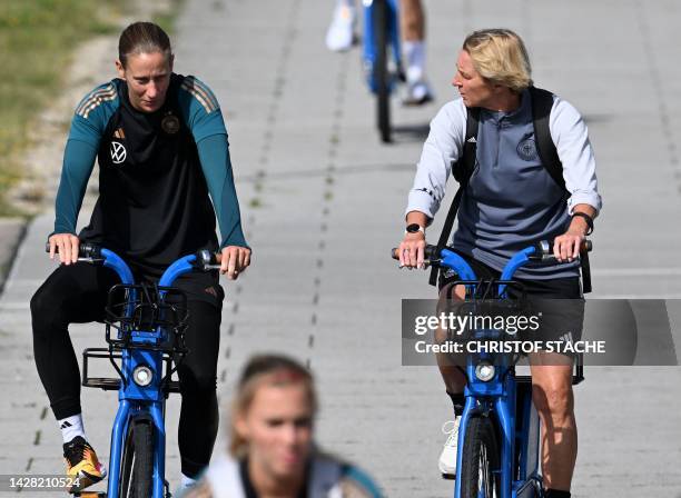 Martina Voss-Tecklenburg , head coach of Germany's women's national football team, talks with the team's goalkeeper Ann-Katrin Berger as they arrive...