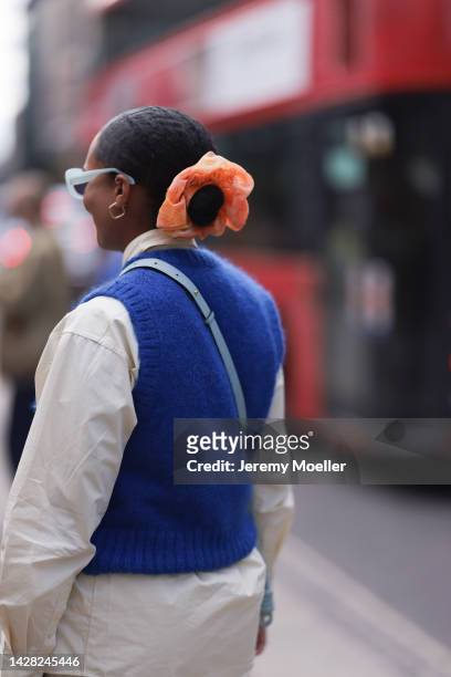 Fashion week guest seen wearing a white blouse, blue sweater vest and an orange hair tie, outside Halpern Show during London Fashion Week, on...