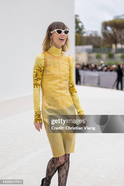 Anya Ziourova wears yellow see trough sleeveless dress, black tights, turtleneck with graphic outside Dior during Paris Fashion Week - Womenswear...