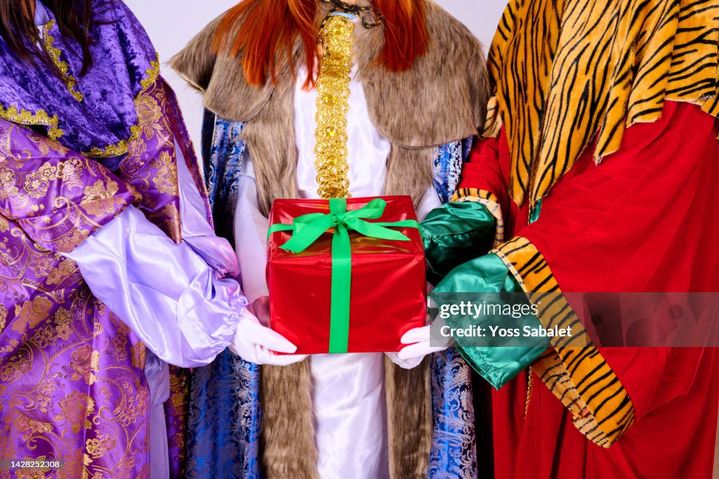 Close-up of three queens holding a christmas present