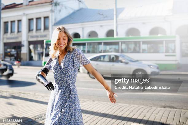 woman in light blue dress dances bachata on sidewalk on street in small town. - bionic arm stock pictures, royalty-free photos & images