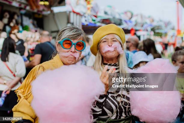 happy senior friends enjoying county fair, having fun with cotton candy. - carousel musical fotografías e imágenes de stock